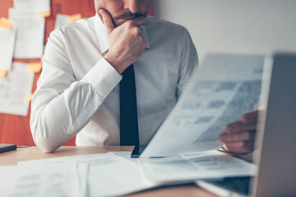 Businessman reading business report document at office desk